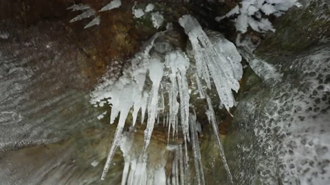 White icicles hang on ceiling of cave. Stalactites formed from frozen water Stock Footage 166565845