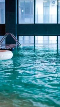 A white inflatable swim ring floats on the turquoise surface of an indoor swi Stock Photos
