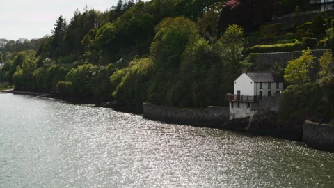 White irish cottage on a sparkling river bank Stock Footage 336772991