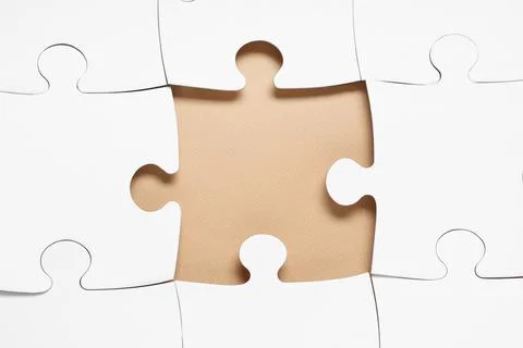 White jigsaw puzzle with missing piece on beige background, closeup Stock Photos