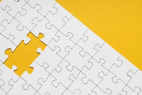 White jigsaw puzzle with missing pieces on yellow background Stock Photos