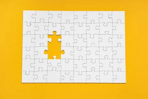 White jigsaw puzzle with missing pieces on yellow background Stock Photos