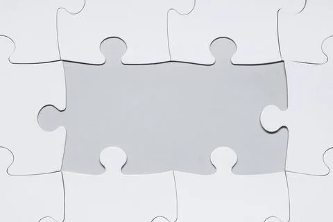 White jigsaw puzzle with missing pieces on grey background Stock Photos