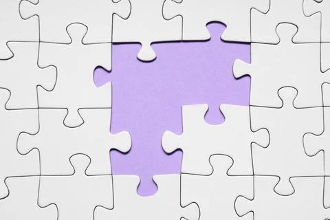 White jigsaw puzzle with missing pieces on purple background Stock Photos