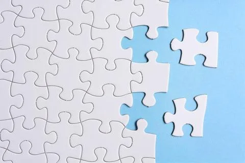 White jigsaw puzzle with some missing pieces on blue background. Copy space. Stock Photos