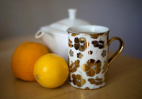 White kettle, cup of tea, orange and lemon. Stock Photos