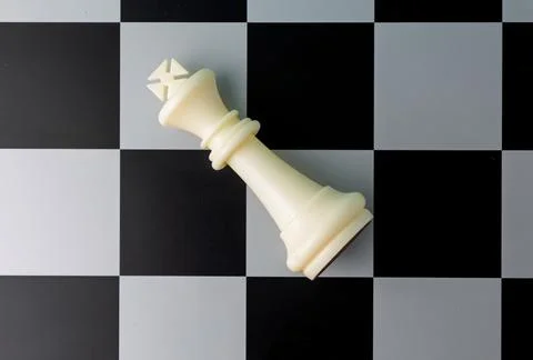 White king lying down defeated on chessboard: signifying checkmate and game.. Stock Photos