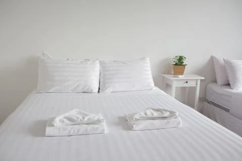White king size bed, two pillows, towel and tree pot plant in bedroom for res Stock Photos