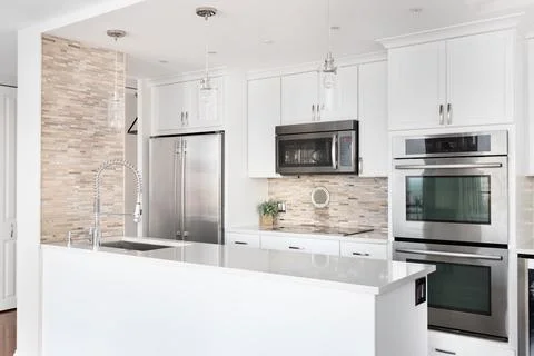 A white kitchen with a brown tile backsplash. Stock-Fotos