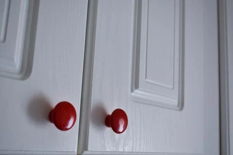 White kitchen cabinet with red knobs Stock Photos