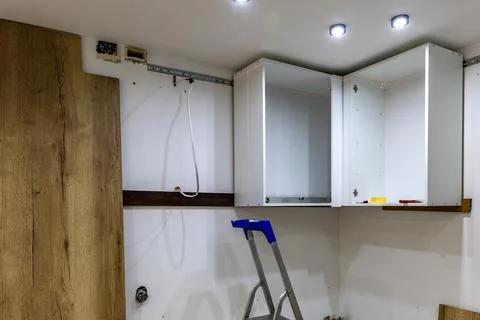 White kitchen cabinets hung on the wall, assembly of custom-made kitchen fu.. Stock Photos