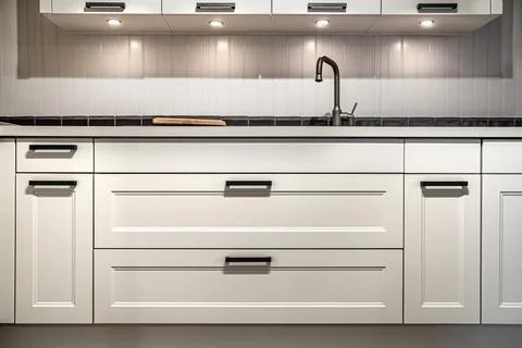 White kitchen cabinets with metal pulls or knobs on the doors. Foto stock