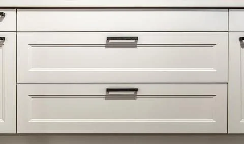 White kitchen cabinets with metal pulls or knobs on the doors. Foto stock