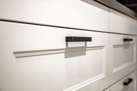 White kitchen cabinets with metal pulls or knobs on the doors. Foto stock