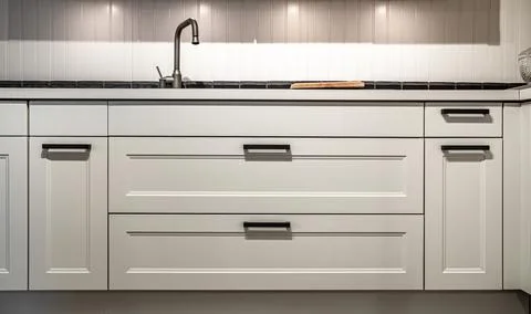 White kitchen cabinets with metal pulls or knobs on the doors. Stock Photos