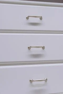 White kitchen cabinets with metal pulls or knobs on the doors close up Stock Photos