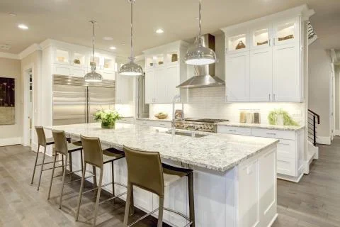 White kitchen design features large bar style kitchen island Stock Photos