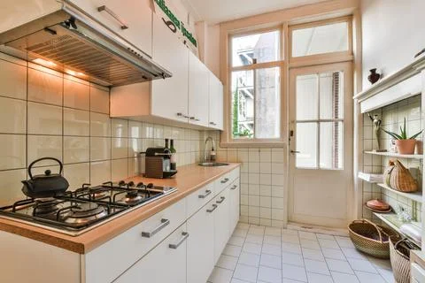 A white kitchen with a stove and a window Stock Photos