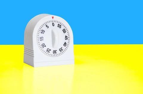 White kitchen timer placed against a vibrant split blue-yellow background Stock Photos