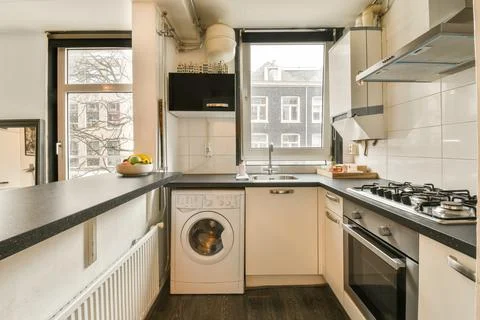 A white kitchen with a washing machine and a window Stock Photos