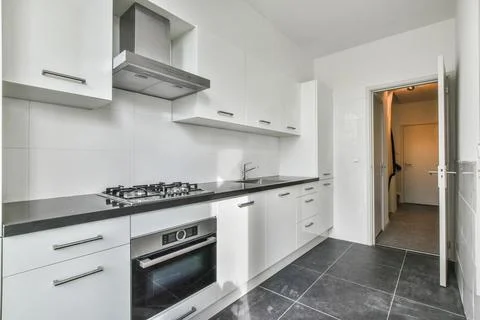 A white kitchen with white cabinets and black counter tops Stock Photos