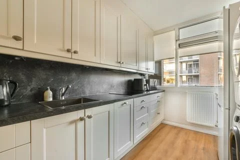 A white kitchen with white cabinets and black counter tops Stock Photos