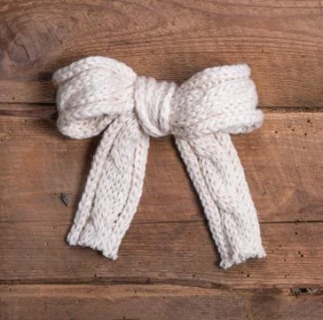 White knitted woolen bow on square wooden background Stock Photos