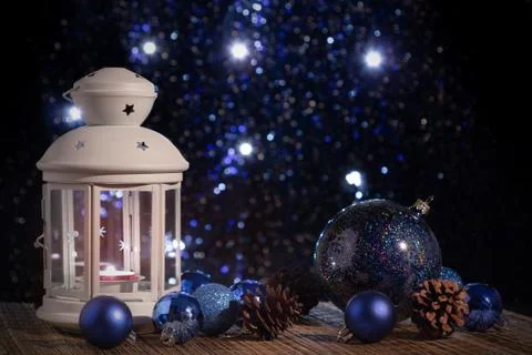 White lantern with a burning candle on the background of the Christmas tree w Stock Photos