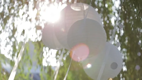 White lanterns blow gently in the breeze against the colored sky Stock Footage 76645474