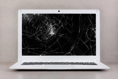 White laptop with a broken screen on a gray background close-up front view... Stock Photos