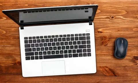 White laptop, computer mouse. Brown wooden table Фото