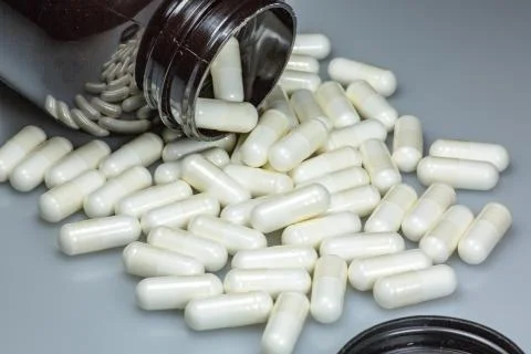 White large pills falling out of a large brown pill bottle Stock Photos