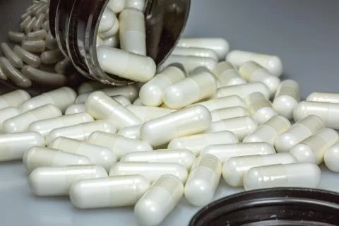 White large pills falling out of a large brown pill bottle Stock Photos