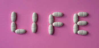 White, large pills or tablets arranged with the text "life" Stock Photos