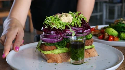 On a white large platter lies a large superfood sandwich with fresh onion rings Stock Footage 205588648