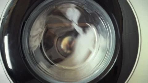 White laundry is being washed in a side-loading washing machine featuring a Stock Footage 331364999