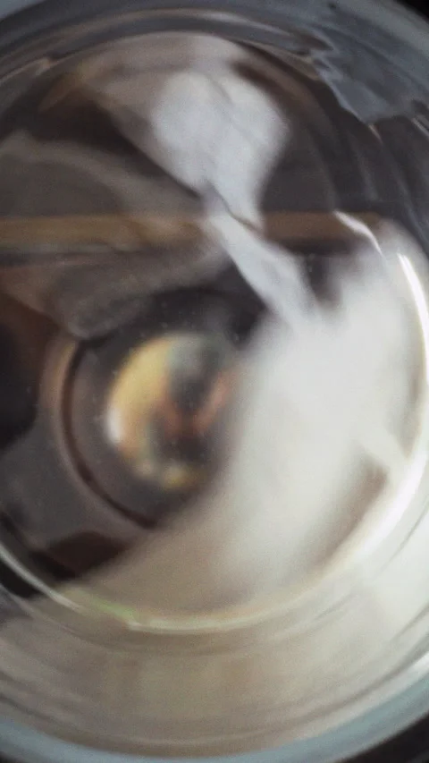 White laundry tumbles in a side-loading washing machine with a clear window Stock Footage 342719612