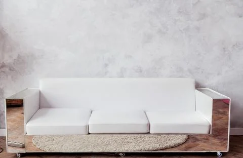 White leather sofa with mirrored frames stands against the background of a gr Stock Photos