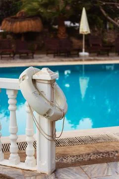 An white life preserver is attached to a railing by a pool Stock Photos
