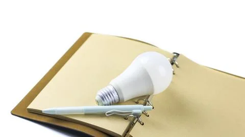White light bulb on an open notebook, symbolizing creativity, innovation, i.. Stock Photos