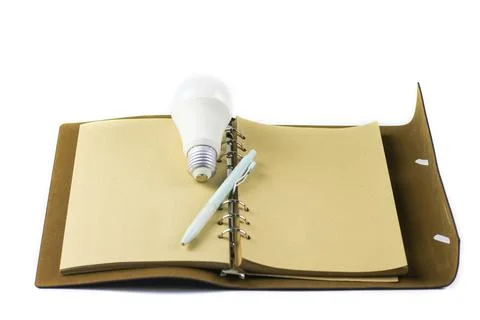 White light bulb on an open notebook, symbolizing creativity, innovation, i.. Stock Photos