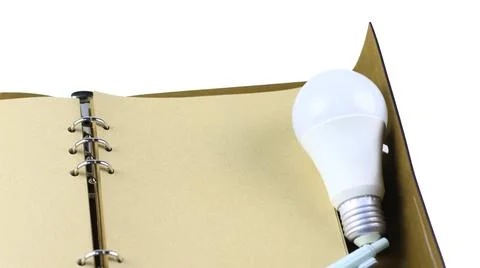 White light bulb on an open notebook, symbolizing creativity, innovation, i.. Stock Photos