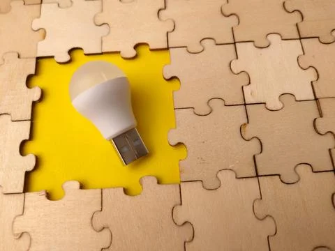 White light bulb placed in the center of a yellow cutout, surrounded by int.. Stock Photos