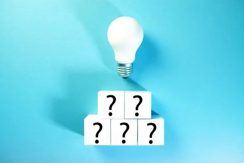White light bulb with question mark on white cubes on blue background. Stock Photos