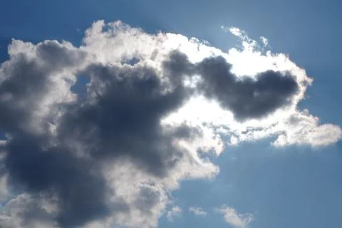 White light fluffy clouds in a blue sky with a solar flare. Stock Photos