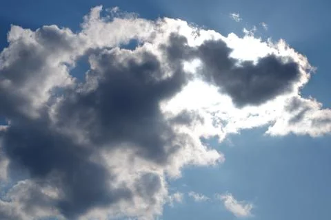 White light fluffy clouds in a blue sky with a solar flare. Foto stock