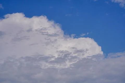 White light fluffy clouds in a blue sky with a solar flare. Stock Photos