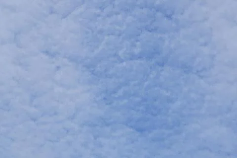 White light fluffy clouds in a blue sky with a solar flare. Stock Photos