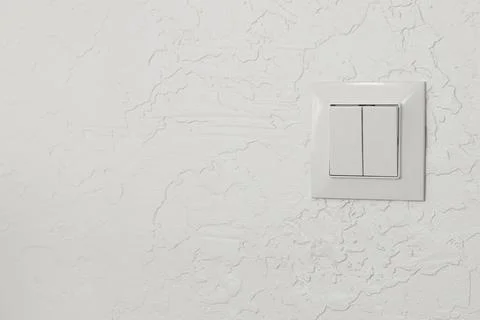 A white light switch plate with two toggle switches mounted on a textured whi Stock Photos