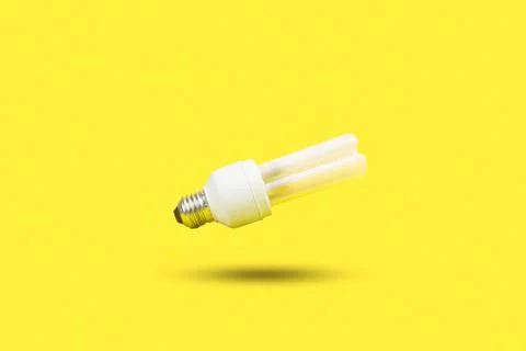 White lightbulb floating on a yellow background with shadow and copy space Stock Photos